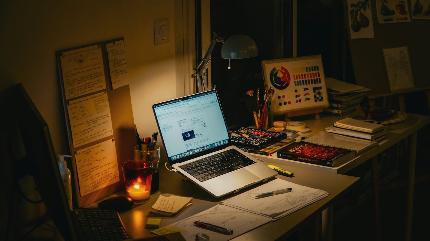 Creative workspace with laptop, art supplies, and notebooks.