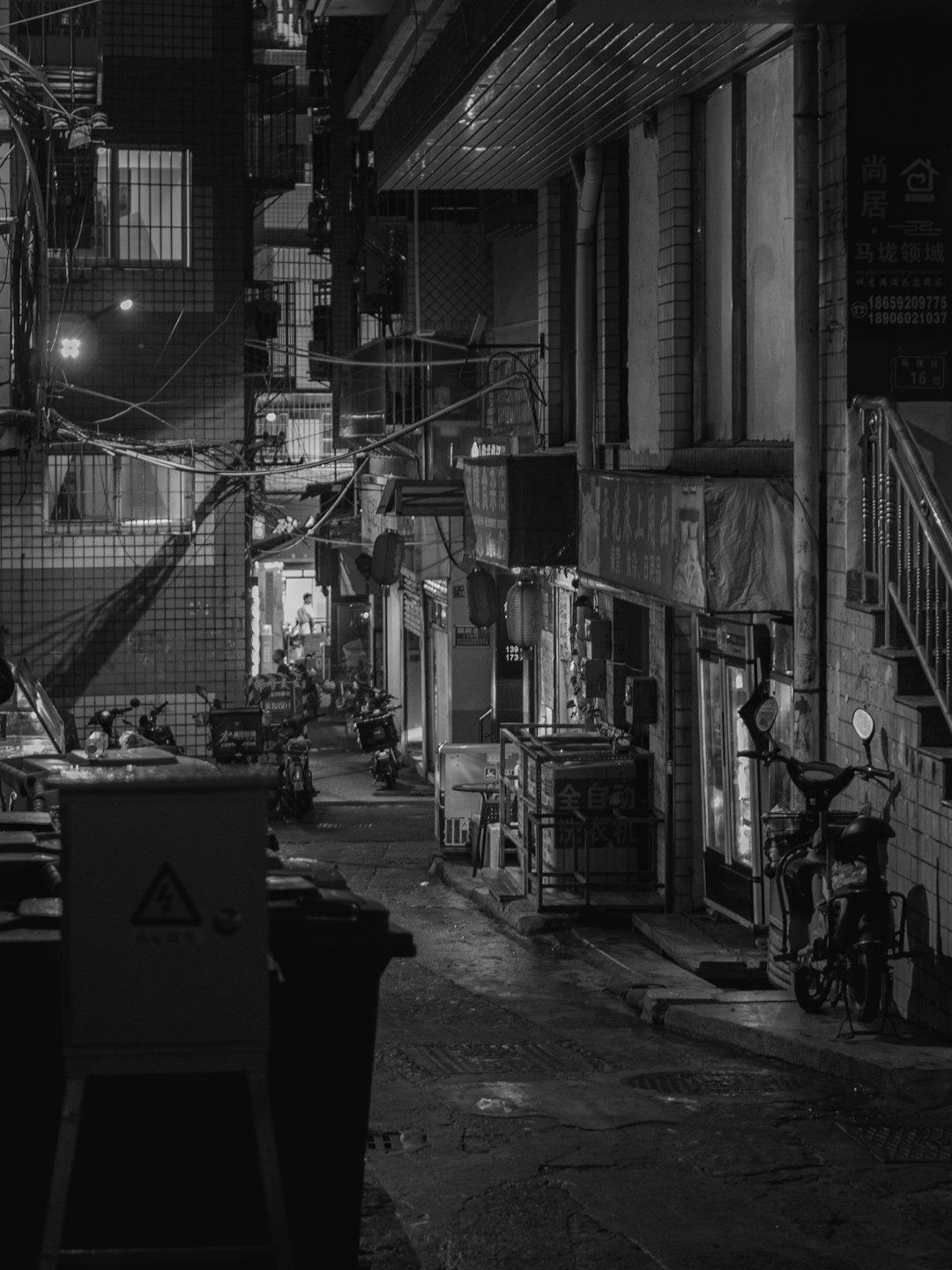 Motorbikes parked in a narrow urban alleyway at night.
