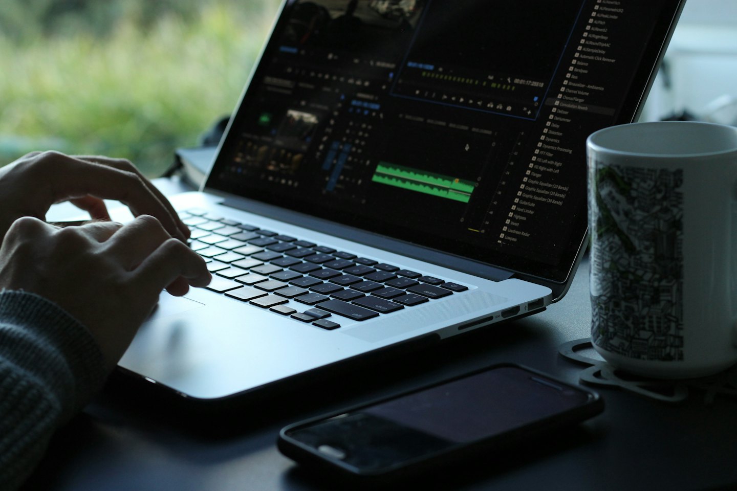 Hands typing on a laptop with video editing software open.